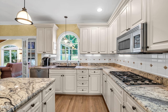 9009 Hometown Dr, Raleigh, NC 27615 - kitchen with stainless steel appliances, healthy amount of natural light, light wood-type flooring, decorative backsplash, and ornamental molding