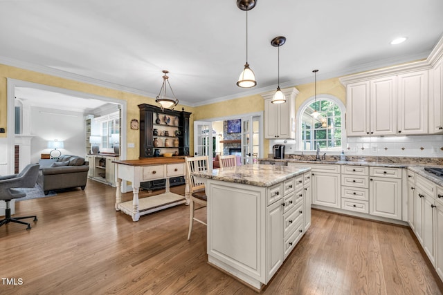 9009 Hometown Dr, Raleigh, NC 27615 - kitchen with light wood-style floors, open floor plan, a center island, crown molding, and hanging light fixtures