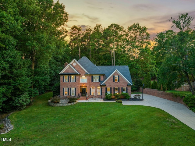 9009 Hometown Dr, Raleigh, NC 27615 - back of house at dusk featuring brick siding, a lawn, and a chimney