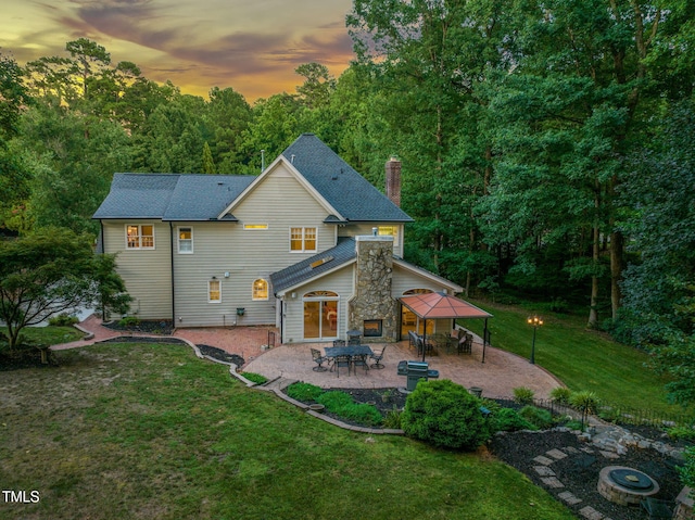 9009 Hometown Dr, Raleigh, NC 27615 - rear view of house featuring a patio area, a yard, a chimney, stone siding, and a forest view