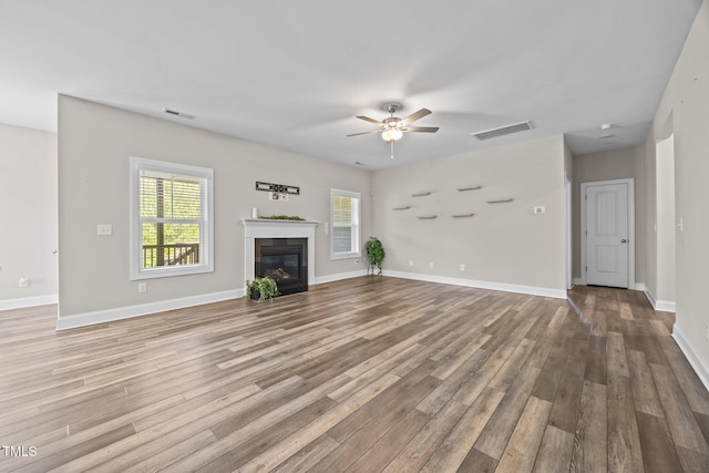 40 Cinnamon Teal Way, Youngsville, NC 27596 - unfurnished living room with a ceiling fan, wood finished floors, and a glass covered fireplace