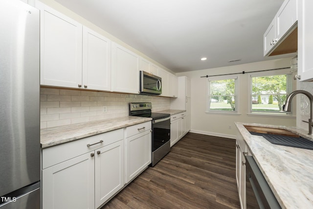 313 13th St, Butner, NC 27509 - kitchen featuring appliances with stainless steel finishes, dark wood finished floors, backsplash, recessed lighting, and white cabinetry