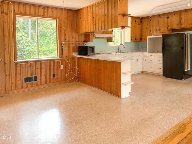 3323 Baugh St, Raleigh, NC 27604 - kitchen with freestanding refrigerator, light countertops, under cabinet range hood, open shelves, and wood walls
