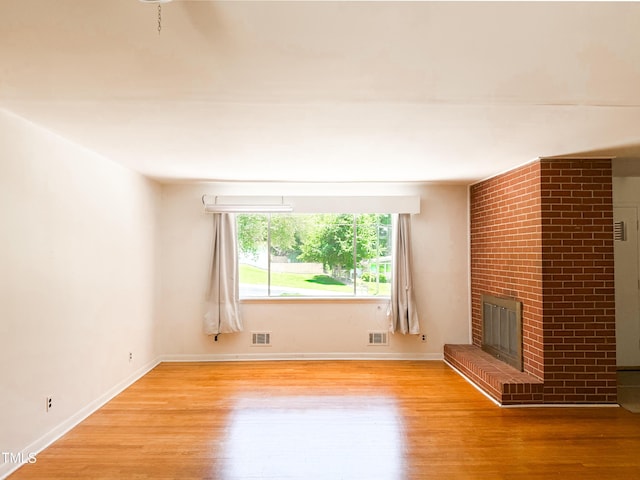 3323 Baugh St, Raleigh, NC 27604 - unfurnished living room featuring wood finished floors and a brick fireplace