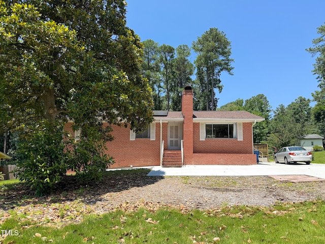 3323 Baugh St, Raleigh, NC 27604 - ranch-style house featuring brick siding, a chimney, solar panels, and entry steps