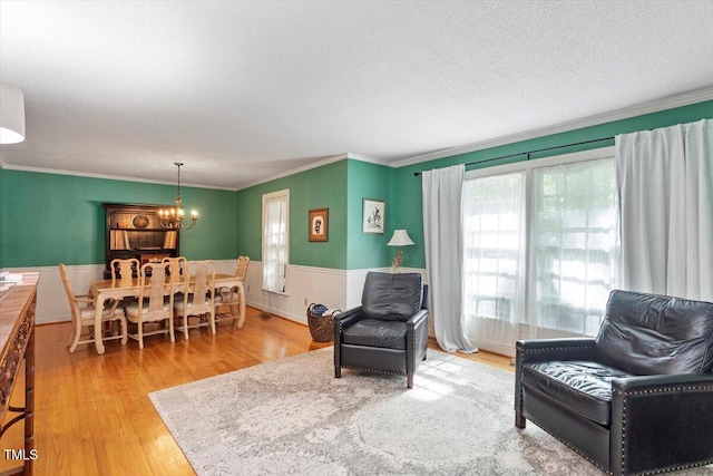 701 Bennington Dr, Raleigh, NC 27615 - living room featuring a chandelier, wainscoting, crown molding, wood finished floors, and a textured ceiling