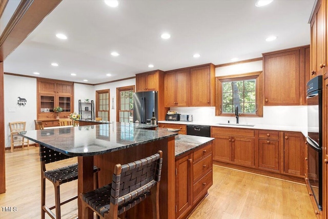 701 Bennington Dr, Raleigh, NC 27615 - kitchen with black appliances, crown molding, a kitchen breakfast bar, light wood-type flooring, and brown cabinets