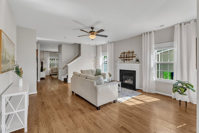 3119 Guiding Light Rd, Raleigh, NC 27610 - living room featuring wood finished floors, a glass covered fireplace, a ceiling fan, and stairway