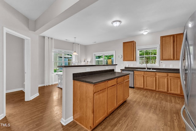 3119 Guiding Light Rd, Raleigh, NC 27610 - kitchen featuring appliances with stainless steel finishes, wood finished floors, a center island, dark countertops, and decorative light fixtures