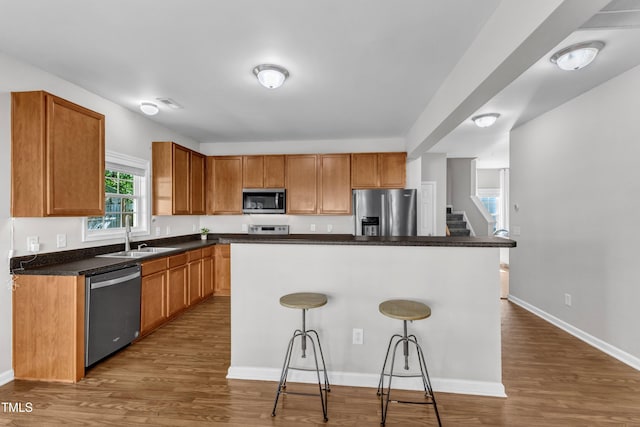3119 Guiding Light Rd, Raleigh, NC 27610 - kitchen with appliances with stainless steel finishes, a kitchen breakfast bar, dark wood finished floors, dark countertops, and a center island