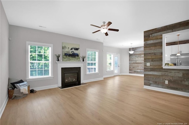 786 Century Dr, Cameron, NC 28326 - unfurnished living room with light wood finished floors, plenty of natural light, a glass covered fireplace, ceiling fan, and wooden walls