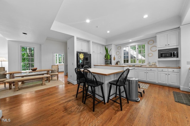 2602 Vintage Hill Ct, Durham, NC 27712 - kitchen with stainless steel microwave, black refrigerator with ice dispenser, white cabinetry, recessed lighting, and ornamental molding