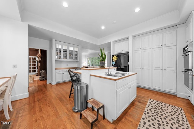 2602 Vintage Hill Ct, Durham, NC 27712 - kitchen with black fridge, white cabinetry, an island with sink, stainless steel double oven, and recessed lighting