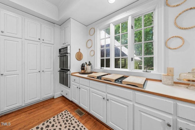 2602 Vintage Hill Ct, Durham, NC 27712 - kitchen featuring ornamental molding, stovetop with downdraft, white cabinets, light countertops, and light wood-style flooring