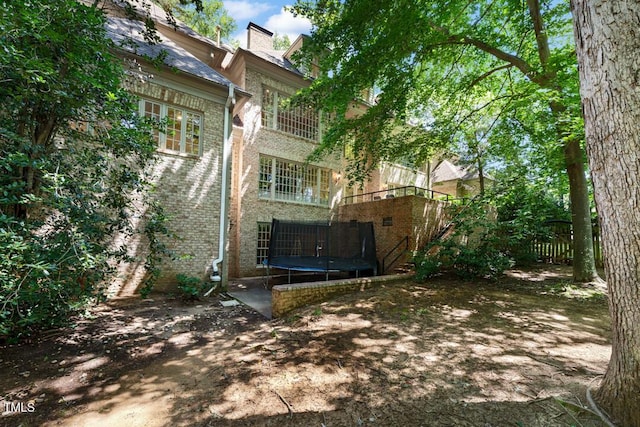 2602 Vintage Hill Ct, Durham, NC 27712 - back of property with a trampoline, brick siding, a chimney, and stairs