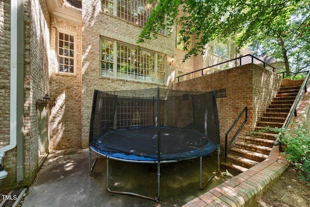 2602 Vintage Hill Ct, Durham, NC 27712 - rear view of property with a trampoline, stairway, and brick siding