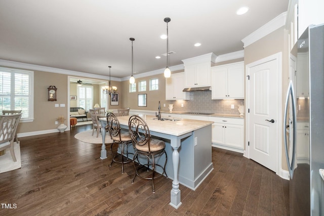 1409 Pulitzer Ln, Durham, NC 27703 - kitchen with freestanding refrigerator, black electric stovetop, a breakfast bar area, white cabinets, and tasteful backsplash