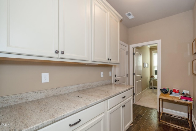 1409 Pulitzer Ln, Durham, NC 27703 - kitchen with dark wood-style floors, white cabinets, and light stone countertops
