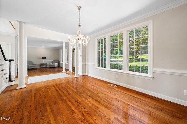 115 Loch Vale Ln, Cary, NC 27518 - unfurnished dining area with stairway, decorative columns, wood finished floors, crown molding, and a chandelier