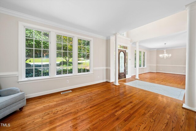 115 Loch Vale Ln, Cary, NC 27518 - unfurnished living room featuring decorative columns, wood finished floors, a chandelier, and ornamental molding