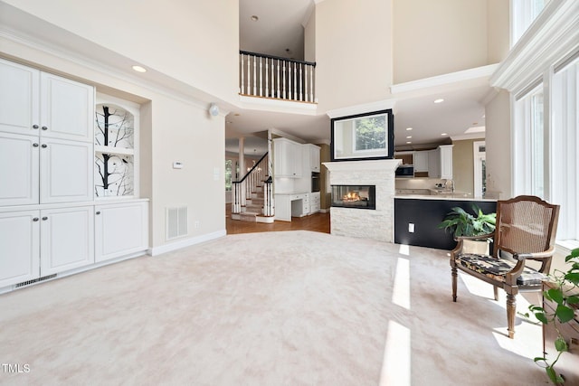 115 Loch Vale Ln, Cary, NC 27518 - living area featuring a high ceiling, plenty of natural light, stairs, light colored carpet, and crown molding