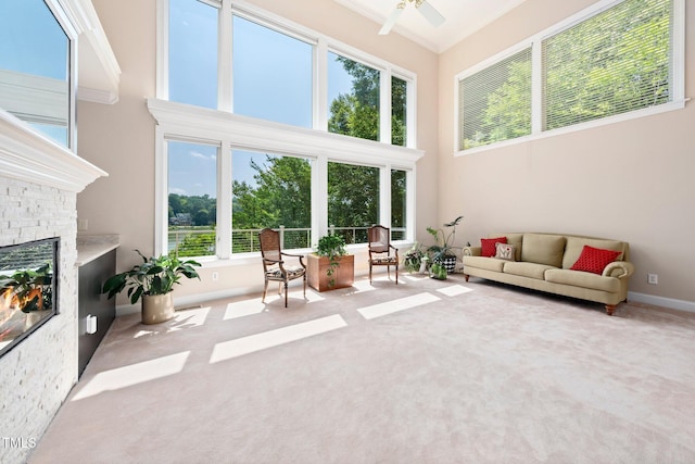 115 Loch Vale Ln, Cary, NC 27518 - carpeted living room featuring a ceiling fan, healthy amount of natural light, a high ceiling, a stone fireplace, and crown molding