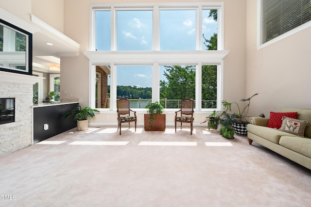 115 Loch Vale Ln, Cary, NC 27518 - carpeted living room featuring a towering ceiling, plenty of natural light, a stone fireplace, and a water view