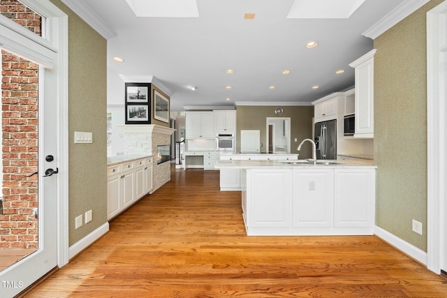 115 Loch Vale Ln, Cary, NC 27518 - kitchen with a skylight, appliances with stainless steel finishes, a peninsula, white cabinetry, and ornamental molding