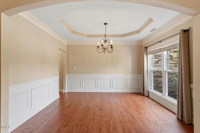 108 Holly Glen Ct, Holly Springs, NC 27540 - spare room with a chandelier, a wainscoted wall, a tray ceiling, arched walkways, and wood finished floors