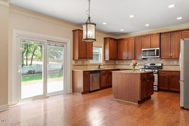 108 Holly Glen Ct, Holly Springs, NC 27540 - kitchen featuring appliances with stainless steel finishes, ornamental molding, backsplash, a kitchen island, and decorative light fixtures