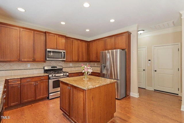 108 Holly Glen Ct, Holly Springs, NC 27540 - kitchen with stainless steel appliances, light wood finished floors, light stone counters, a center island, and ornamental molding