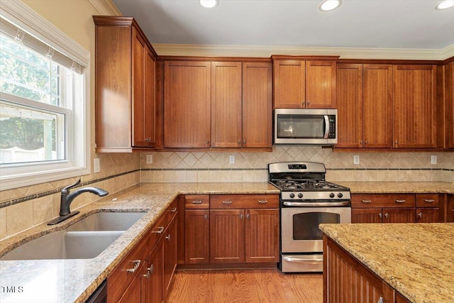 108 Holly Glen Ct, Holly Springs, NC 27540 - kitchen featuring appliances with stainless steel finishes, light stone counters, light wood-style floors, brown cabinetry, and recessed lighting