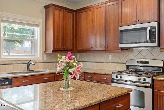 108 Holly Glen Ct, Holly Springs, NC 27540 - kitchen featuring appliances with stainless steel finishes, light stone countertops, brown cabinets, decorative backsplash, and crown molding