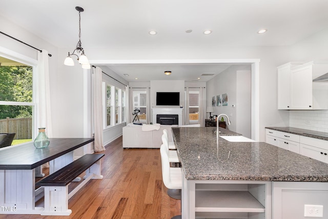 1502 Spring Overlook Ln, Hillsborough, NC 27278 - kitchen with white cabinetry, light wood finished floors, a fireplace, a center island with sink, and black electric stovetop