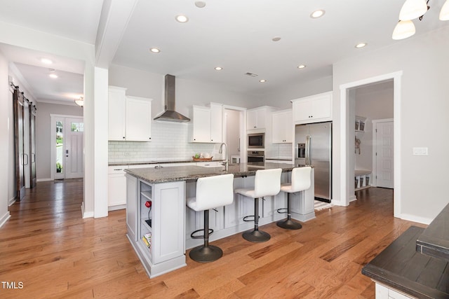 1502 Spring Overlook Ln, Hillsborough, NC 27278 - kitchen with appliances with stainless steel finishes, wall chimney range hood, a breakfast bar area, decorative backsplash, and a kitchen island with sink
