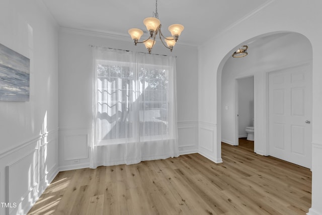 11309 Shadow Elms Ln, Raleigh, NC 27614 - unfurnished dining area featuring arched walkways, a chandelier, light wood-style flooring, ornamental molding, and a decorative wall
