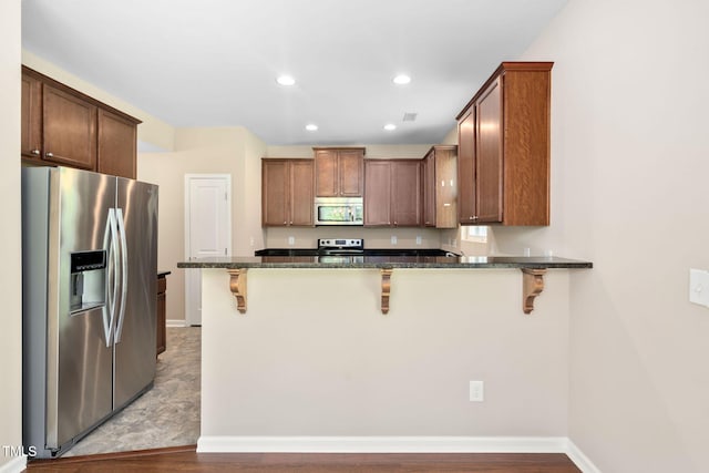 3417 Cardinal Lake Dr, Durham, NC 27704 - kitchen with stainless steel appliances, dark stone countertops, a breakfast bar area, a peninsula, and recessed lighting