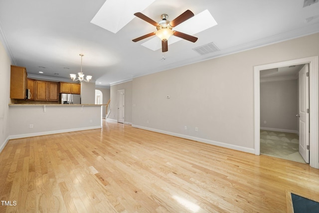 2022 Chandler Village Dr, Graham, NC 27253 - unfurnished living room with a skylight, crown molding, a ceiling fan, a chandelier, and light wood-style floors