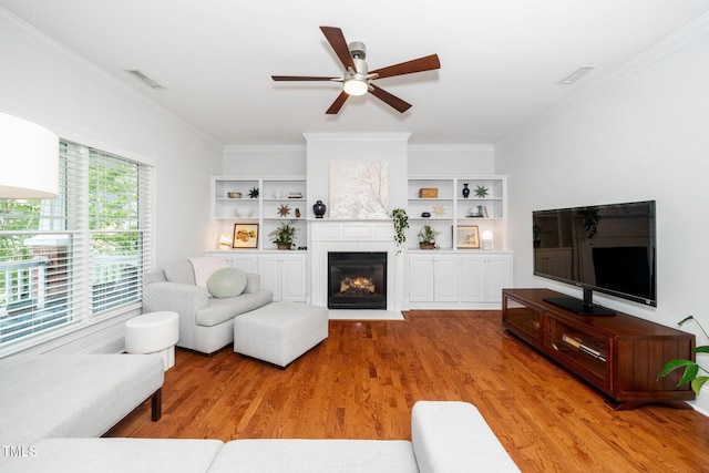 104 Homegate Cir, Apex, NC 27502 - living room featuring light wood-type flooring, a ceiling fan, ornamental molding, and a glass covered fireplace