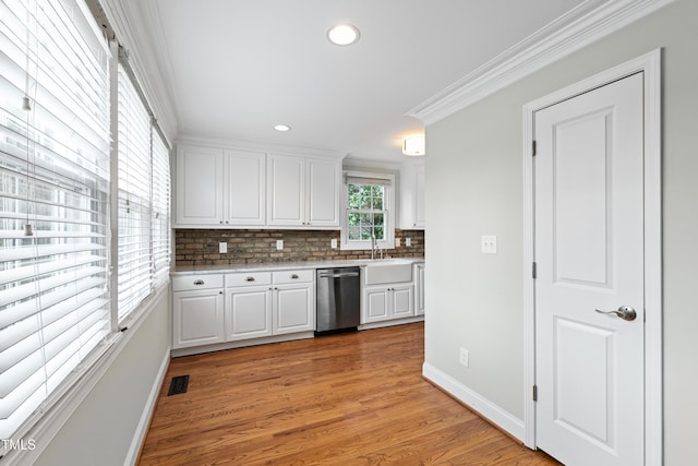 625 New Rd, Raleigh, NC 27608 - kitchen featuring stainless steel dishwasher, backsplash, white cabinetry, light countertops, and light wood-style flooring