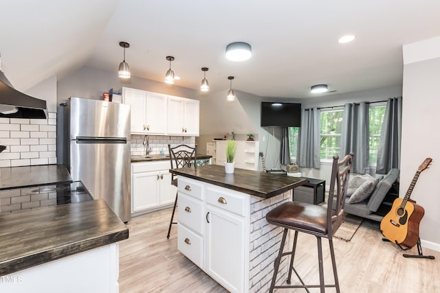 7216 Rabbit Run, Wake Forest, NC 27587 - kitchen featuring freestanding refrigerator, a breakfast bar, white cabinets, tasteful backsplash, and lofted ceiling