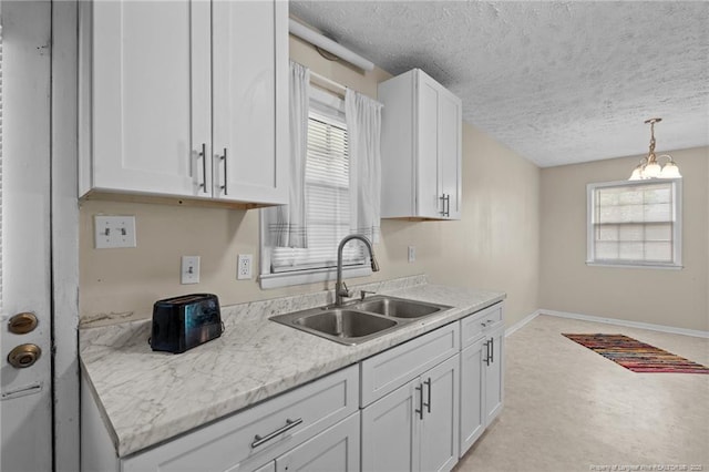 3649 Marcliff Rd, Hope Mills, NC 28348 - kitchen with a textured ceiling, white cabinets, light countertops, plenty of natural light, and hanging light fixtures