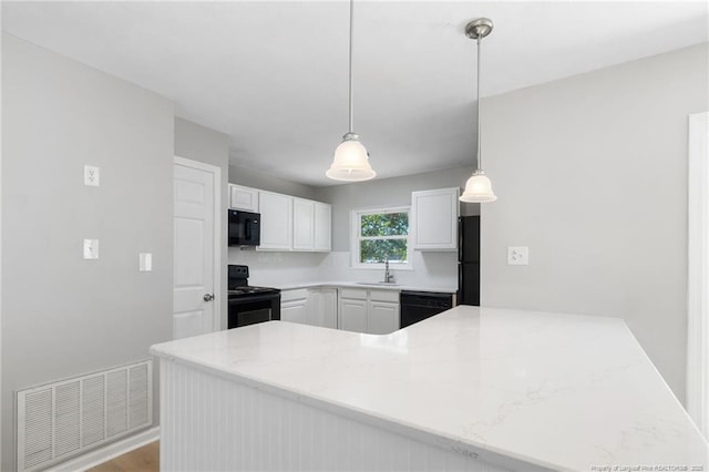 1809 Wendover Dr, Fayetteville, NC 28304 - kitchen with black appliances, white cabinets, hanging light fixtures, a peninsula, and light stone counters