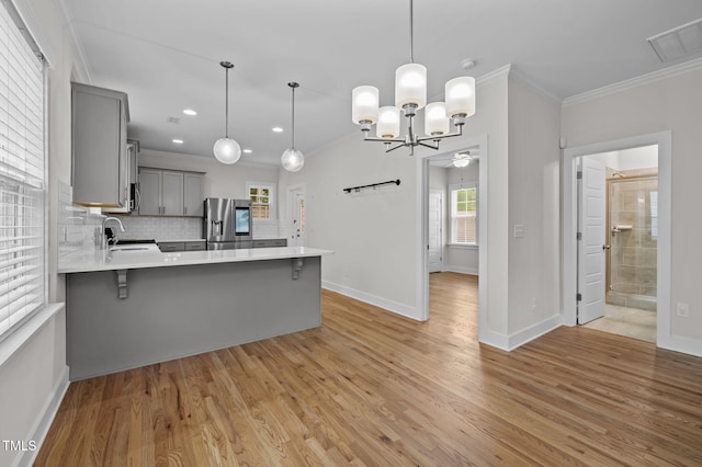1819 Nixon St, Durham, NC 27707 - kitchen featuring gray cabinetry, stainless steel fridge, crown molding, light countertops, and a kitchen breakfast bar