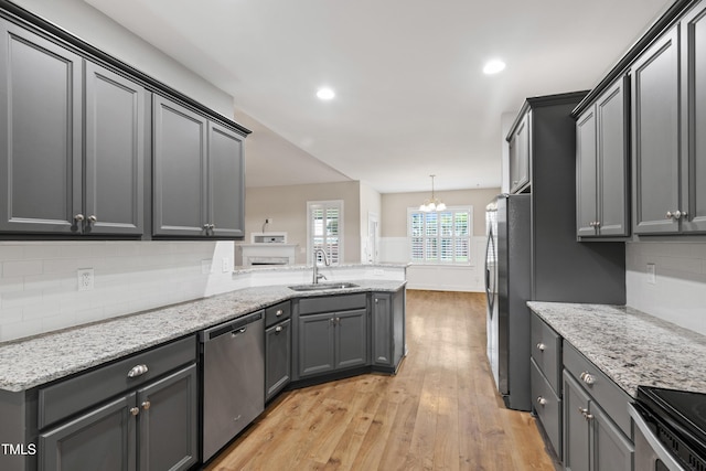24 Windchime Ct, Clayton, NC 27527 - kitchen featuring stainless steel appliances, light wood finished floors, a peninsula, decorative backsplash, and light stone counters