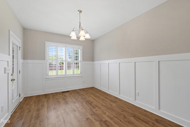 24 Windchime Ct, Clayton, NC 27527 - unfurnished dining area with a chandelier, a decorative wall, wood-type flooring, and wainscoting