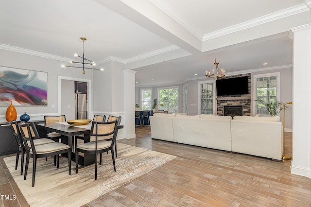 119 Florentino Ct, Clayton, NC 27527 - dining room featuring a chandelier, light wood finished floors, decorative columns, ornamental molding, and a fireplace
