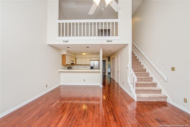 400 Cypress Trace Dr, Fayetteville, NC 28314 - unfurnished living room with a towering ceiling, stairs, wood finished floors, and ceiling fan