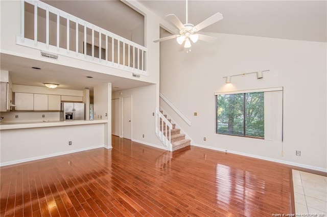 400 Cypress Trace Dr, Fayetteville, NC 28314 - unfurnished living room with high vaulted ceiling, stairway, wood finished floors, and ceiling fan