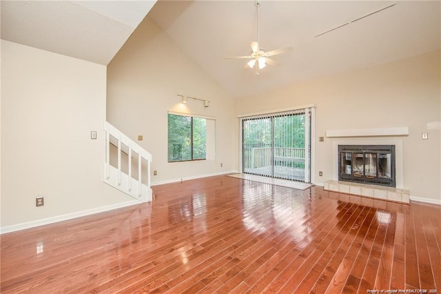 400 Cypress Trace Dr, Fayetteville, NC 28314 - unfurnished living room featuring ceiling fan, stairs, high vaulted ceiling, wood finished floors, and a tiled fireplace